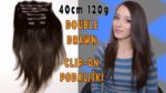 Estensioni per capelli clip-on double drawn 40 cm 120 g, immagine di una donna con capelli lunghi e lisci, sfondo blu e grigio.